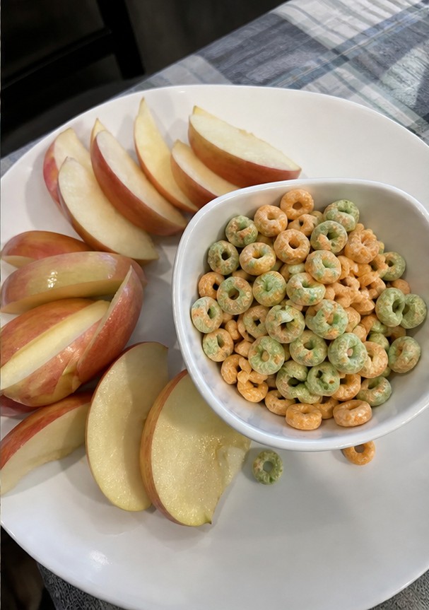 Cereal being poured into a bowl with plain yogurt and banana slices