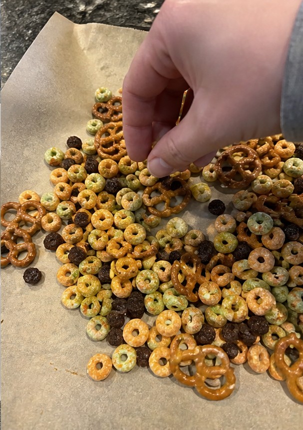 A homemade cereal snack mix with dried fruit and seeds on a parchment-lined tray
