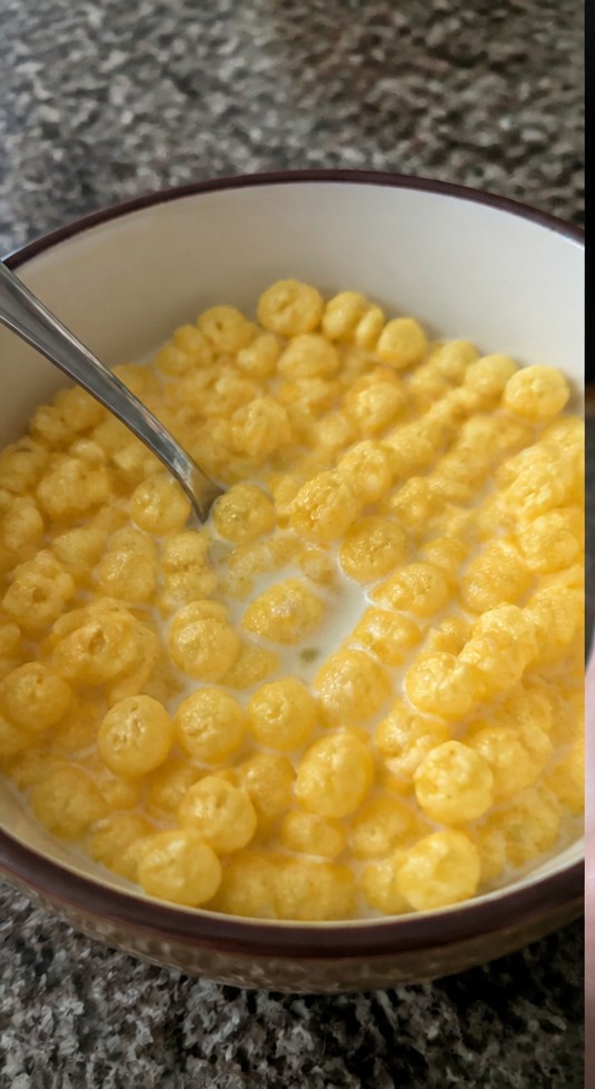 A simple bowl of golden cereal with milk on a wooden breakfast table