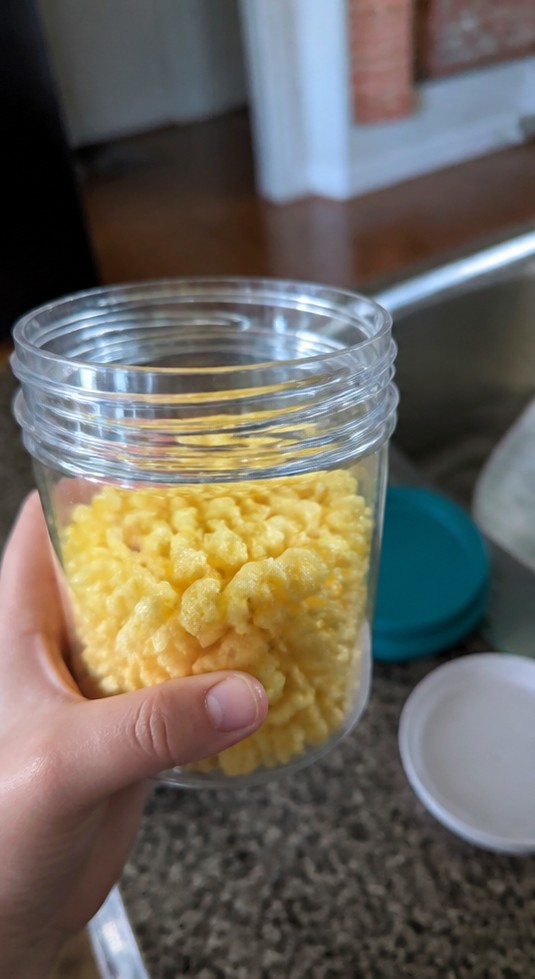 Cereal being poured into a bowl with plain yogurt and banana slices