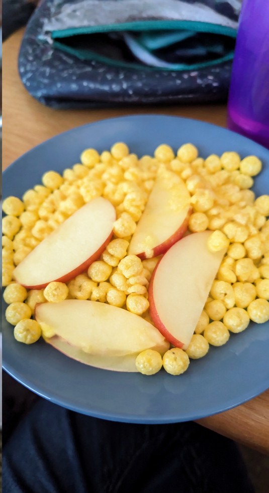 A homemade cereal snack mix with dried fruit and seeds on a parchment-lined tray