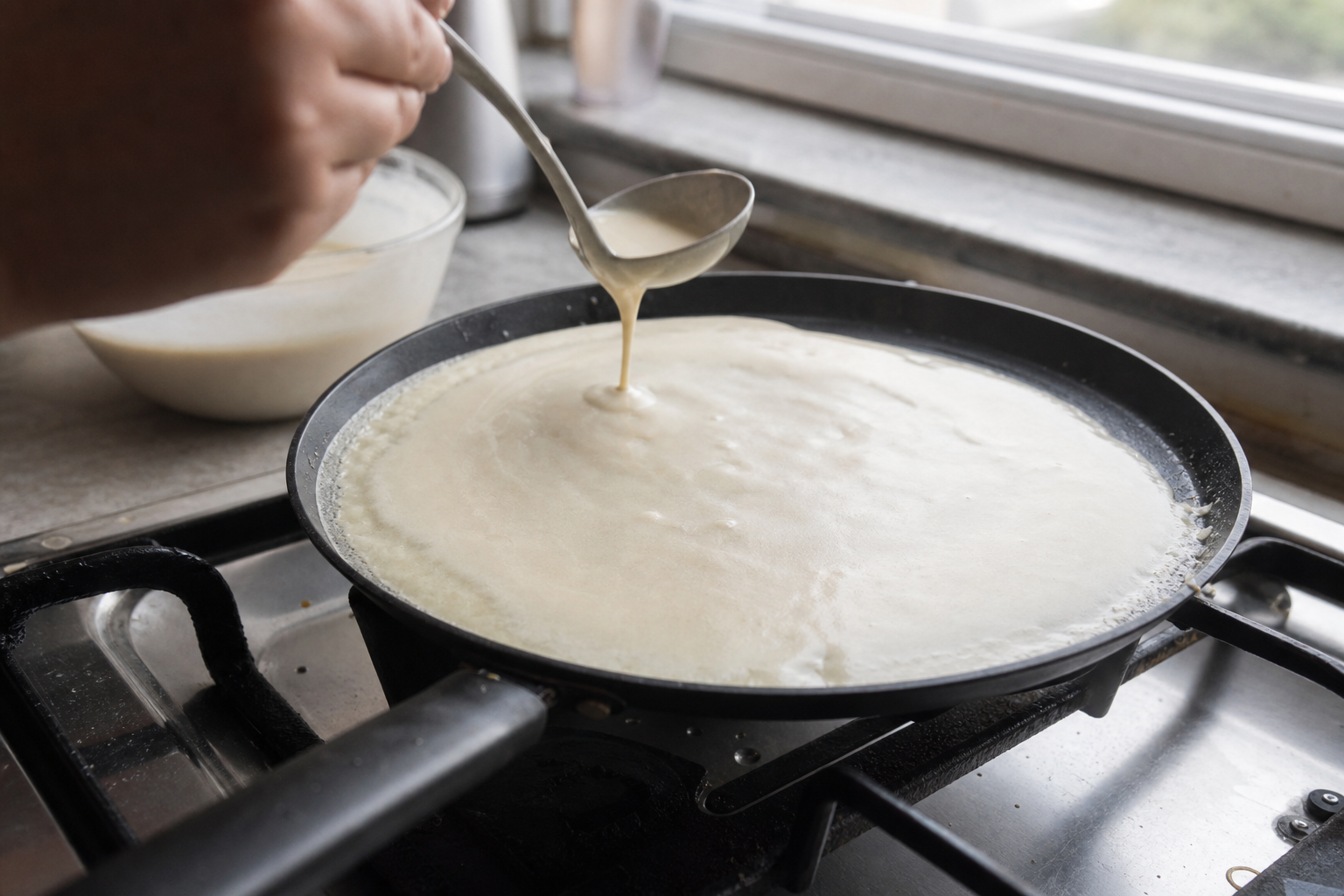 Thin crepe batter spreading in a wide home pan