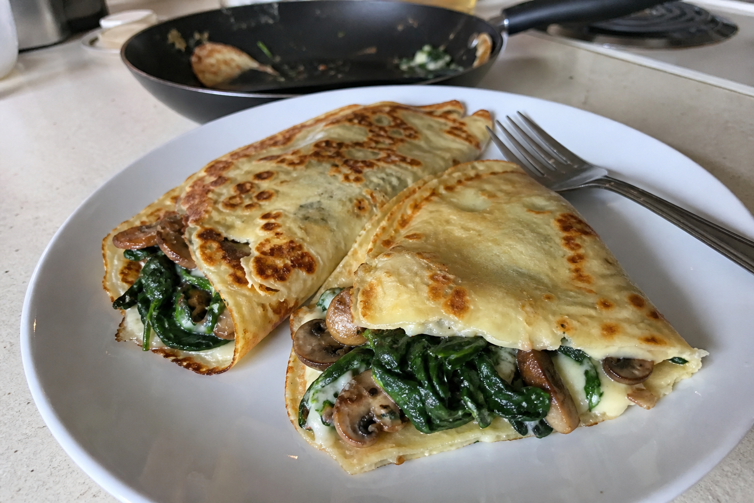 Folded savory crepes with spinach mushrooms and cheese on a plate