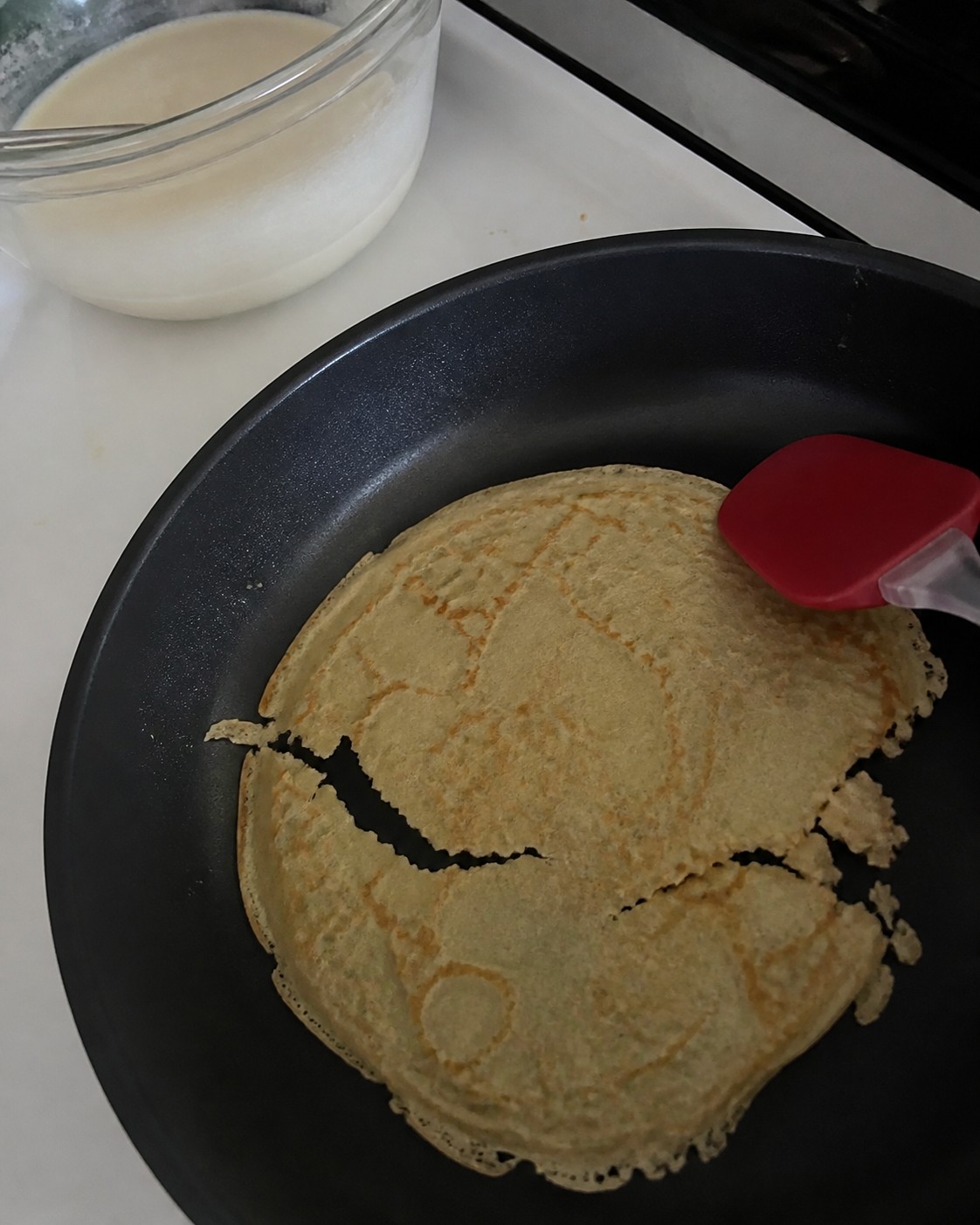 A thin crepe tearing while being lifted in a skillet