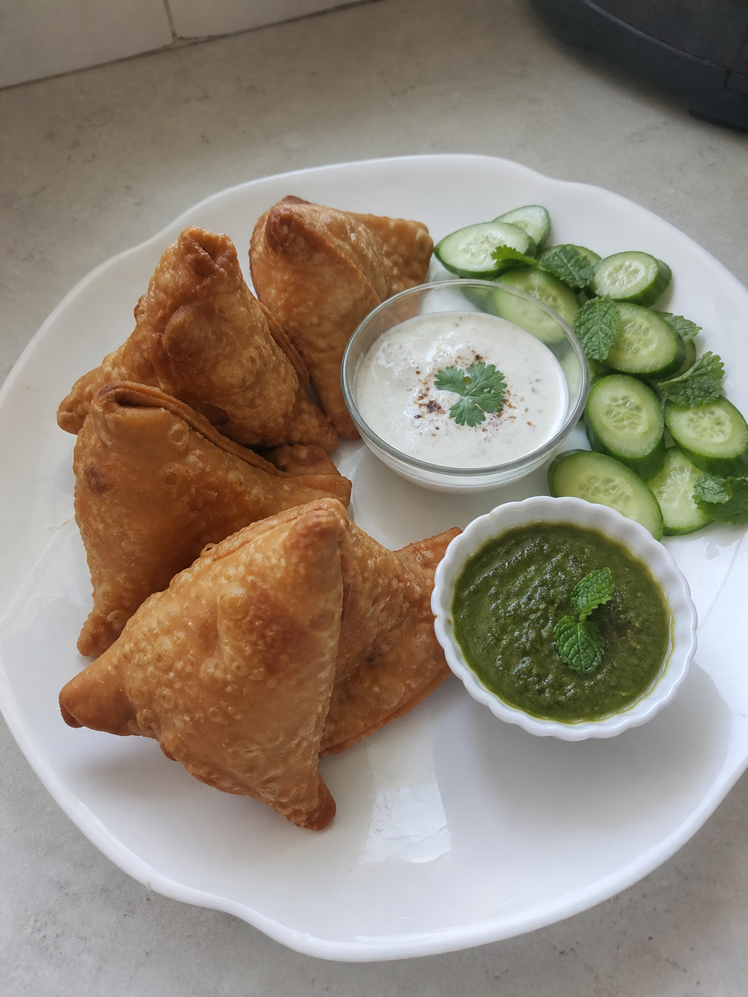Crisp samosas served with cucumber, mint chutney and yogurt dip