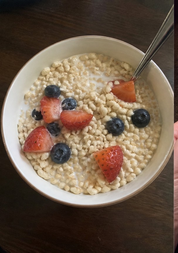 Cereal being poured into a bowl with plain yogurt and banana slices