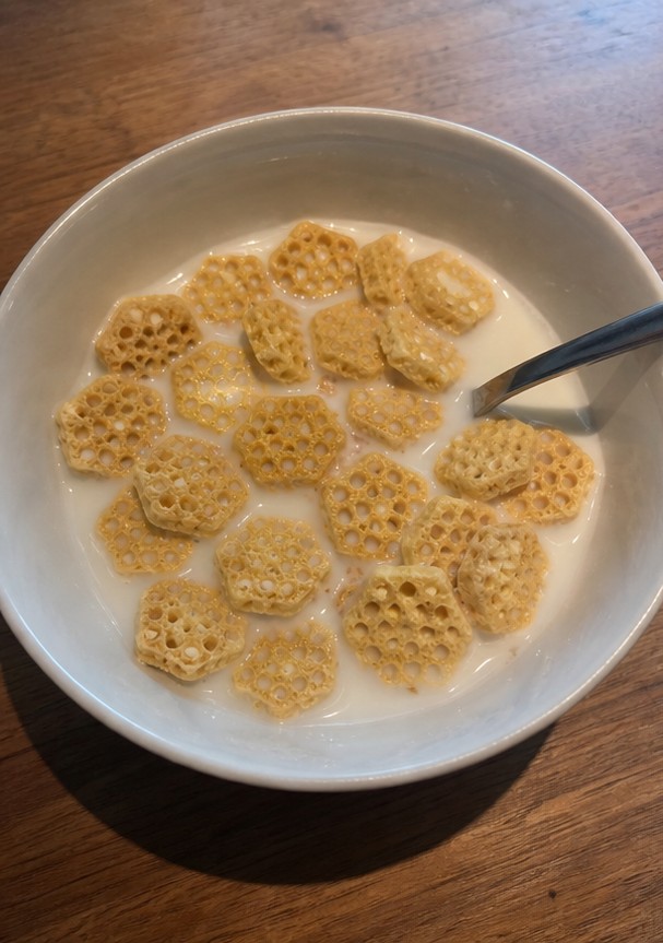 A simple bowl of golden cereal with milk on a wooden breakfast table