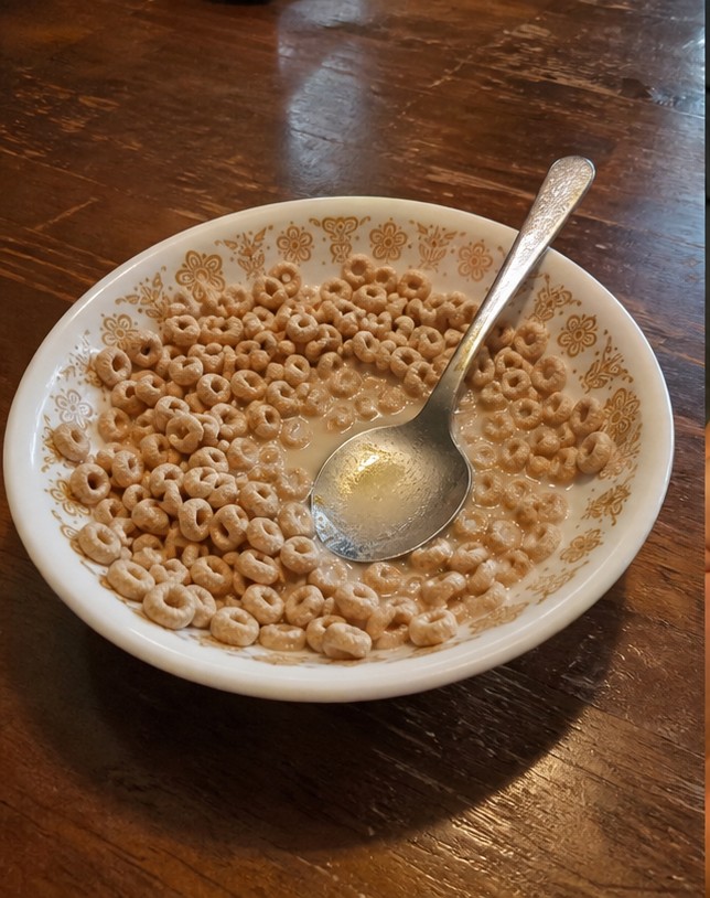 A simple bowl of golden cereal with milk on a wooden breakfast table