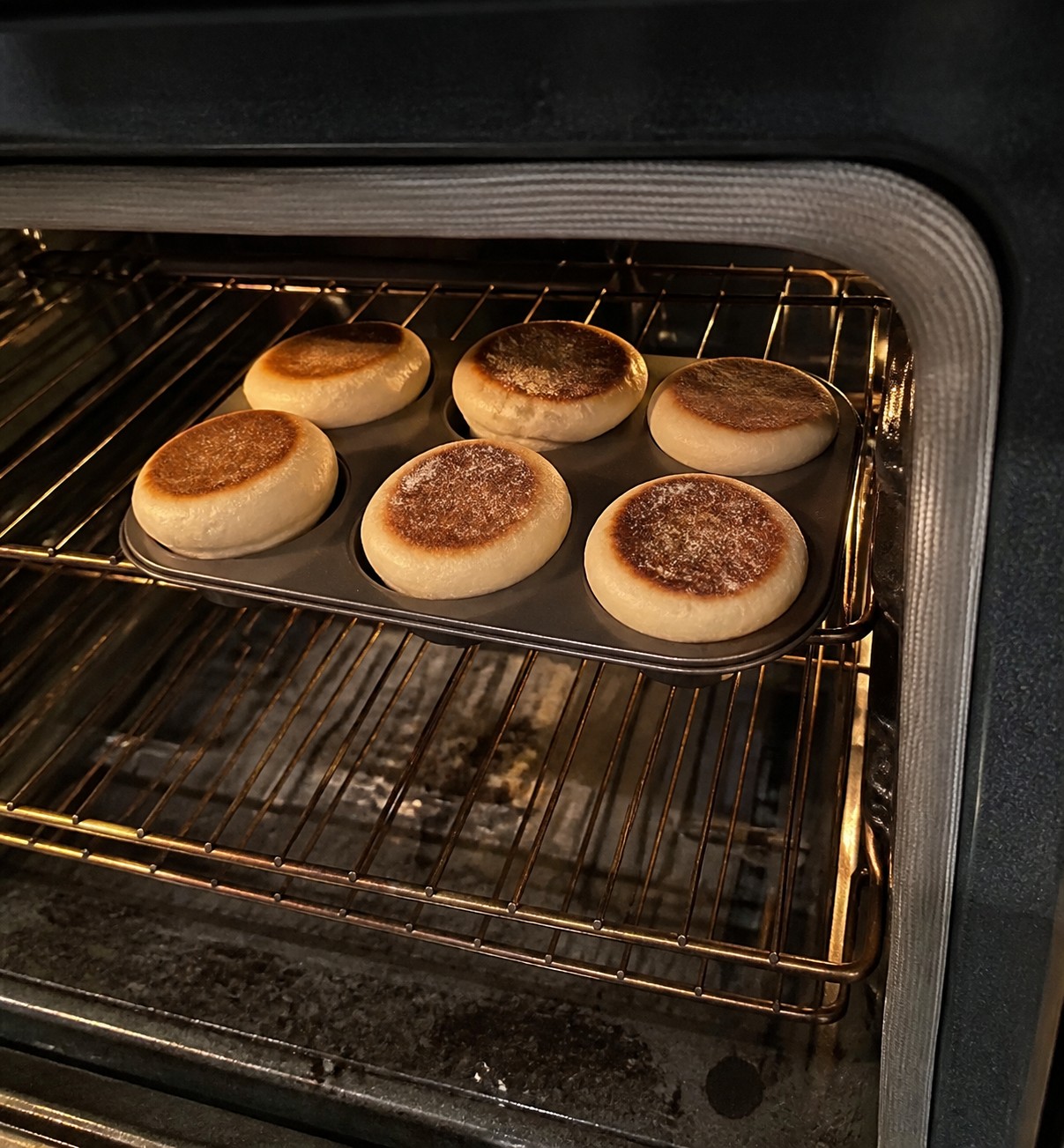 Muffins browning unevenly in a pan on an oven rack