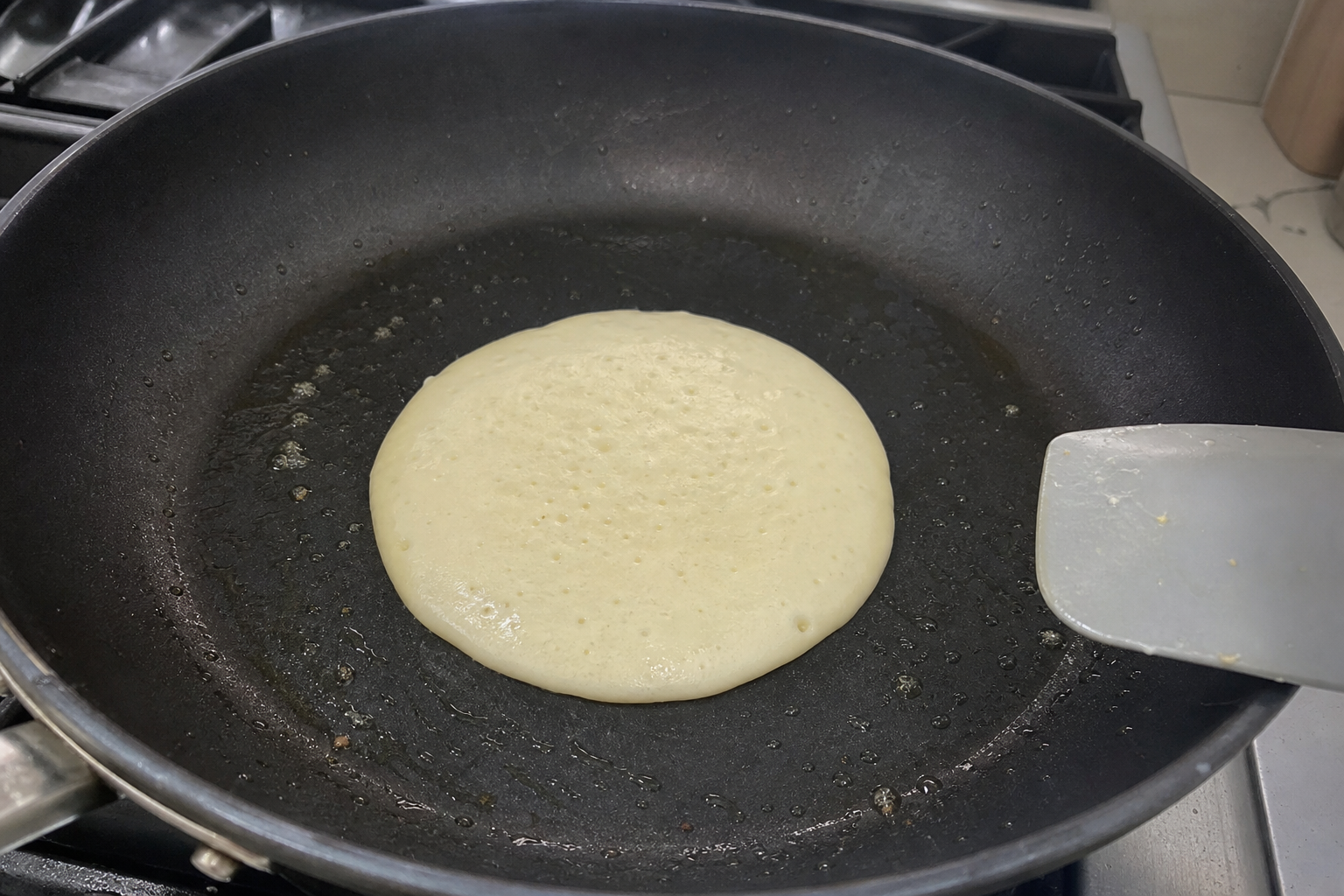 Person cooking pancakes in a frying pan on a stove