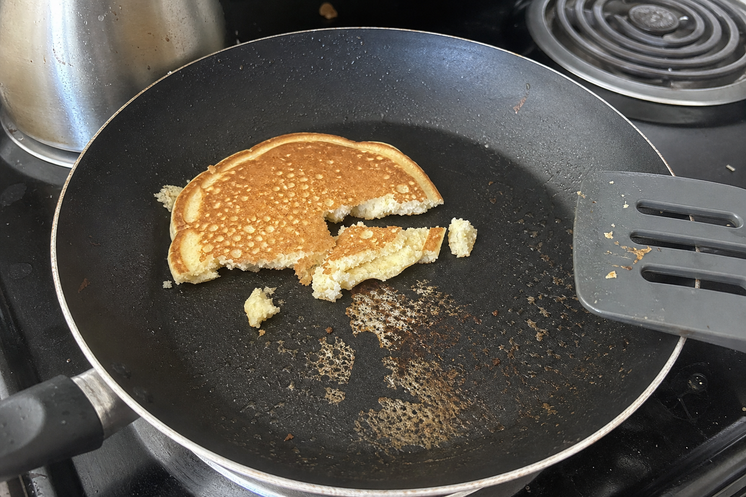 Pancake torn while sticking to a nonstick skillet, with cooked residue left on the pan
