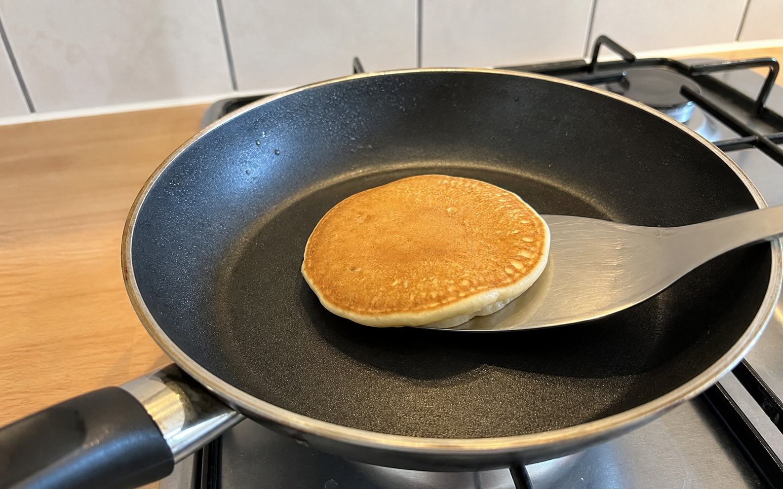 Pancake being lifted from a dark skillet with a spatula