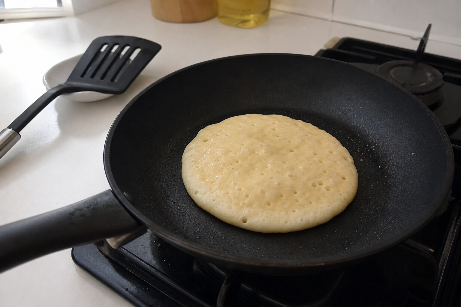 Pancake cooking with a pale edge in a home skillet