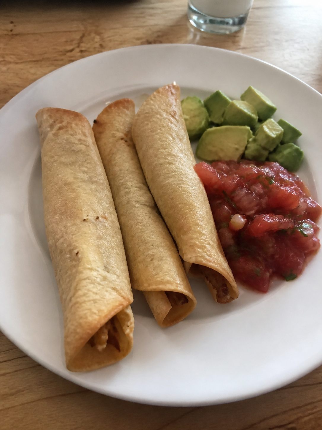 Small crisp taquitos with salsa and avocado slices