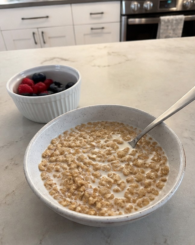 A simple bowl of golden cereal with milk on a wooden breakfast table