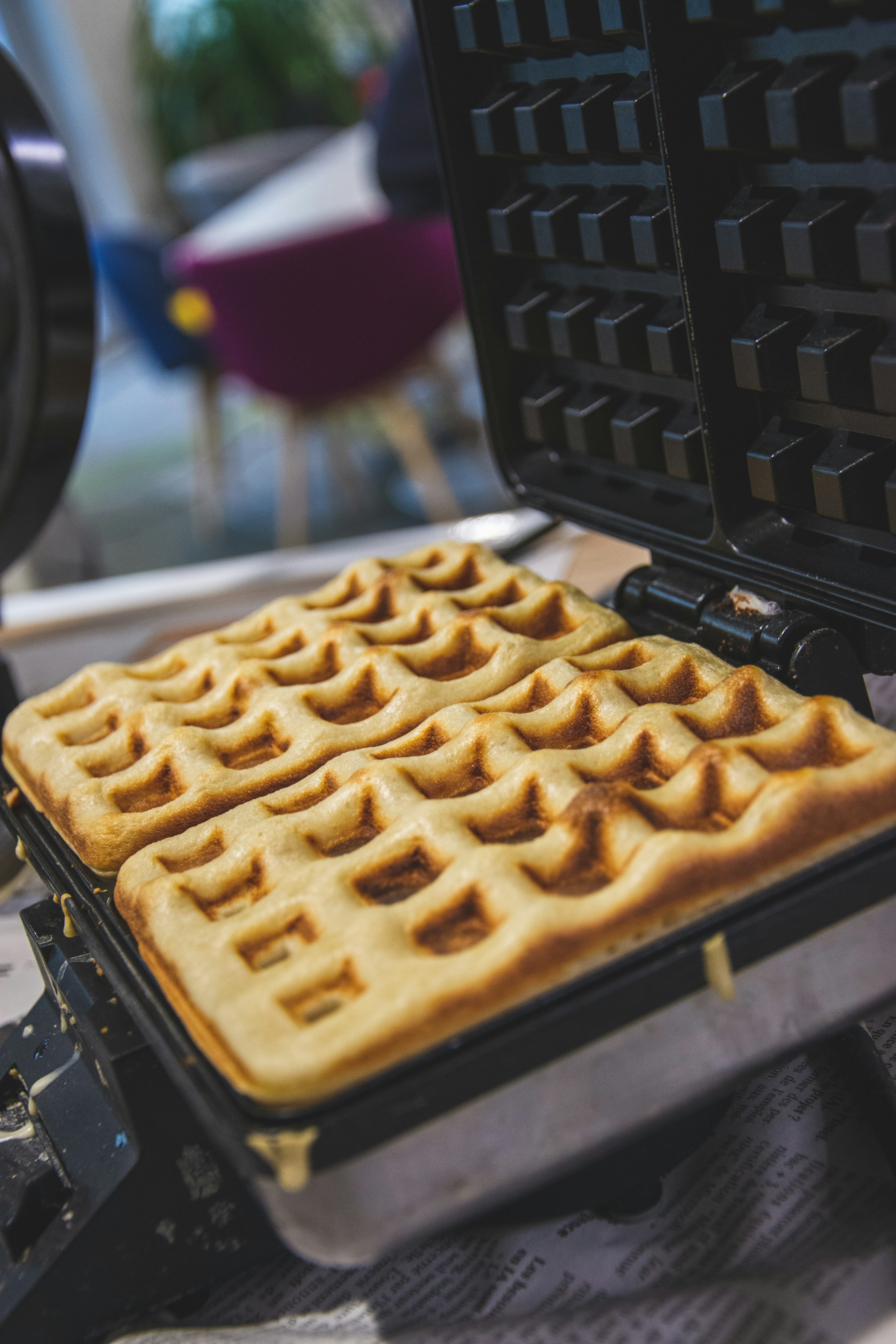 Golden protein waffle cooking in an open round waffle maker