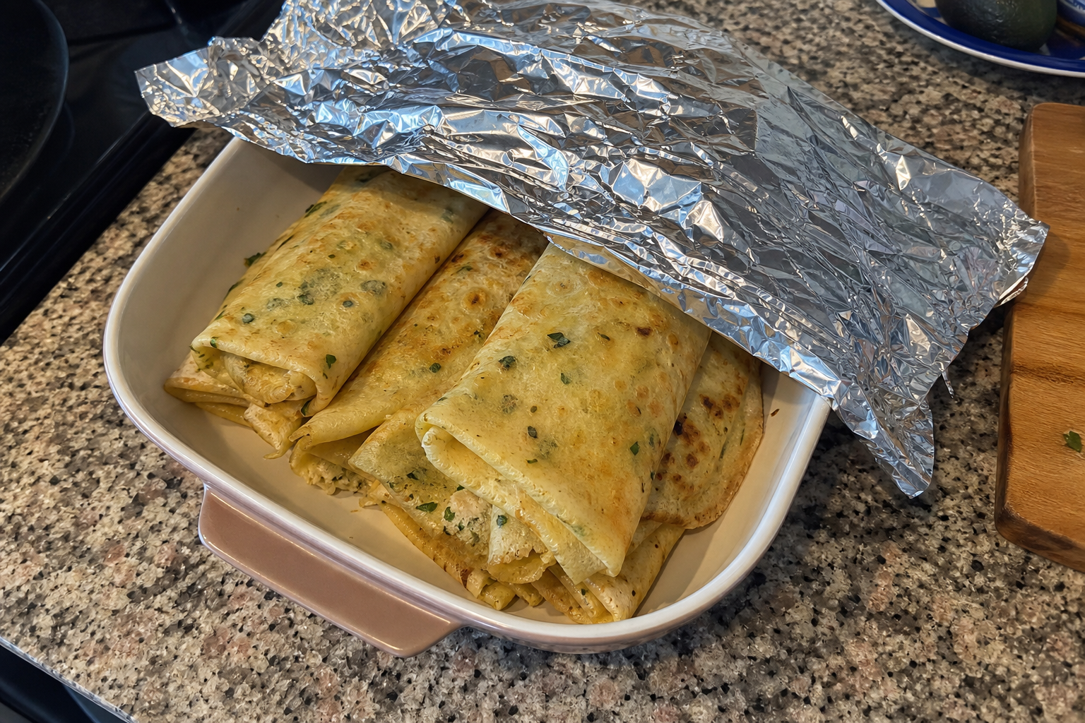 Folded savory crepes in a covered baking dish ready for gentle oven reheating