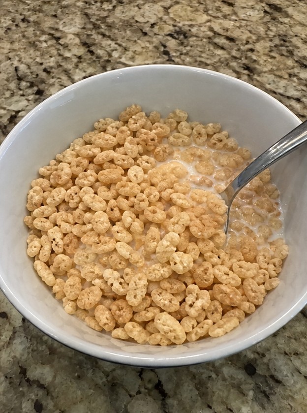 A simple bowl of golden cereal with milk on a wooden breakfast table