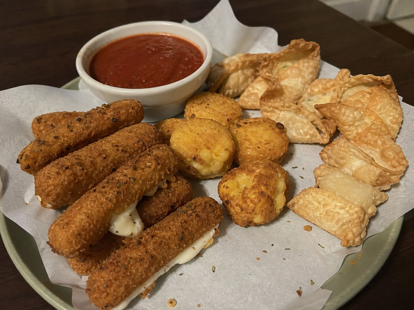 Casual plate of mozzarella sticks, cheese bites and wontons with marinara