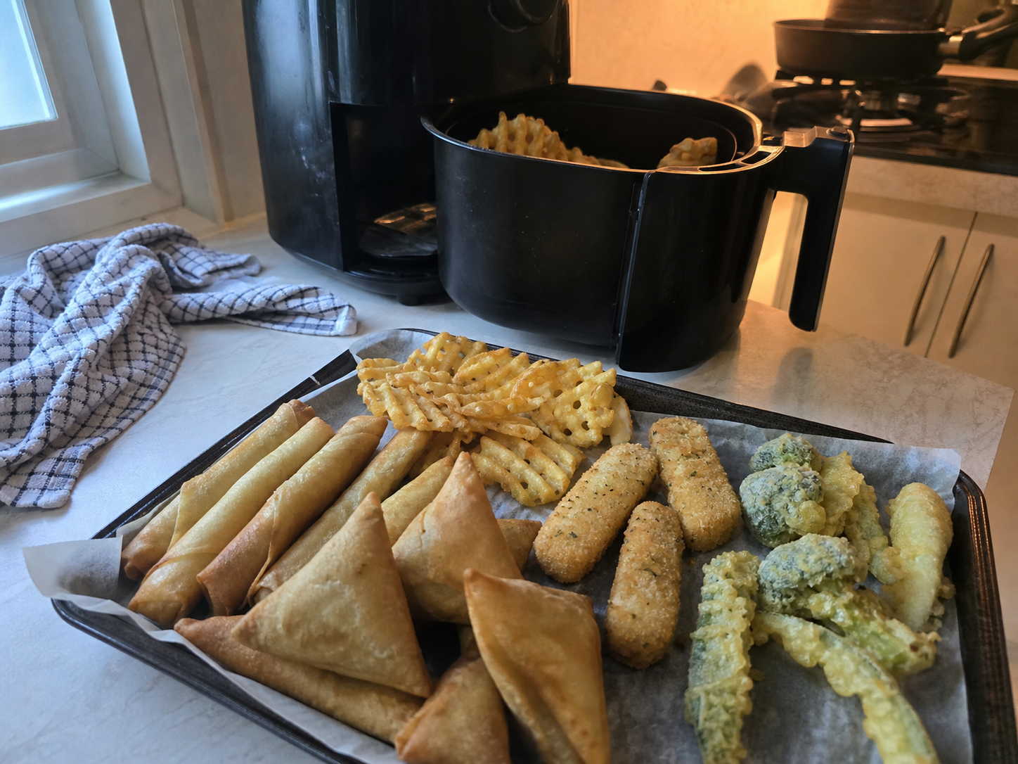 A casual home-kitchen assortment of crisp frozen snacks beside a basket air fryer