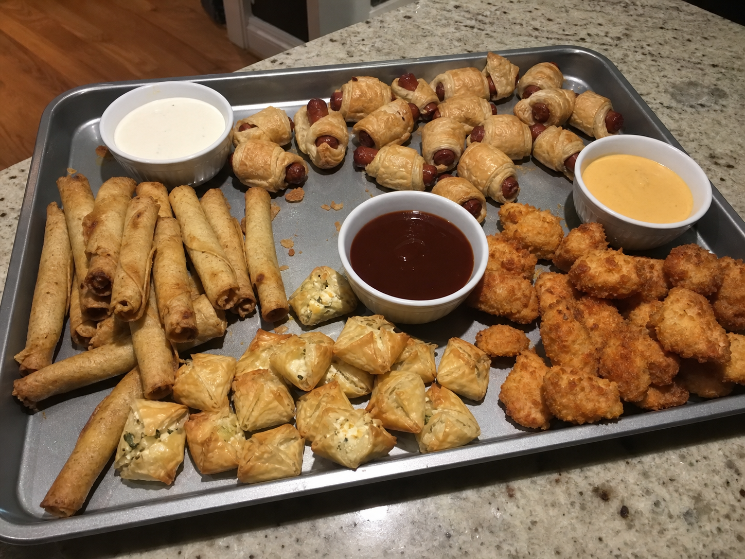 A casual tray of air-fried taquitos, pastry bites and small appetizers