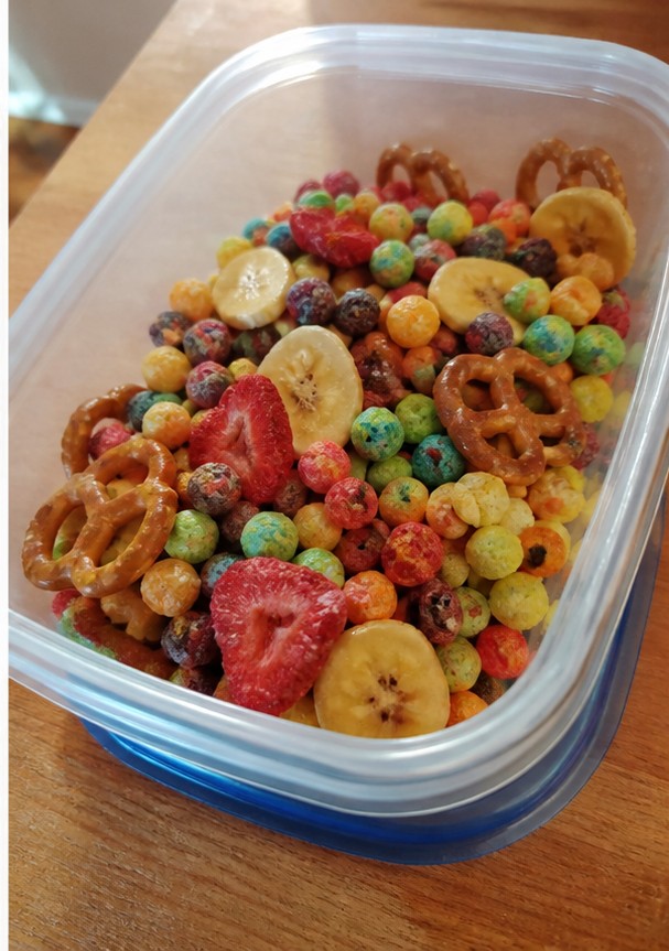 A homemade cereal snack mix with dried fruit and seeds on a parchment-lined tray